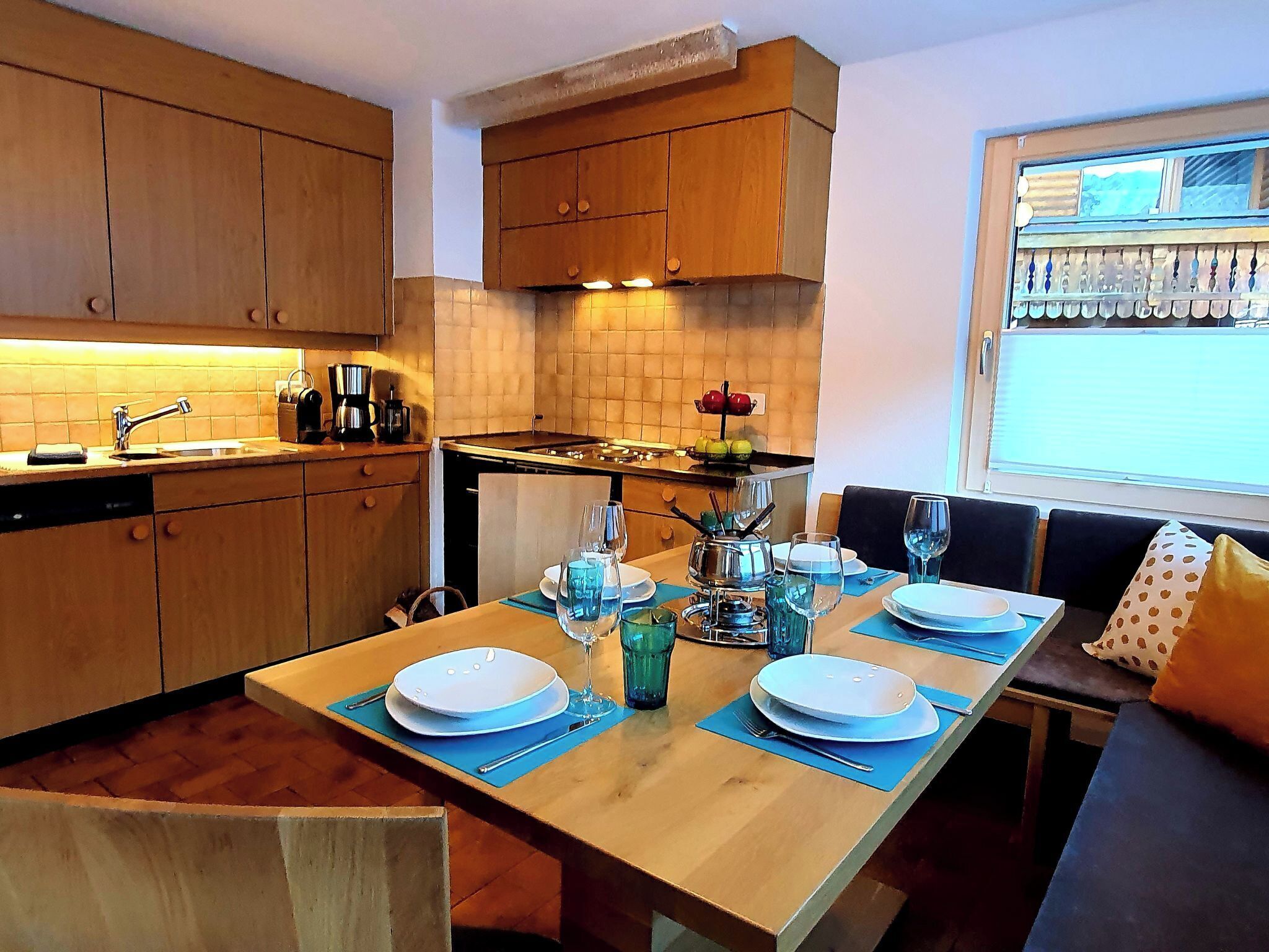 Una cucina moderna con mobili in legno, un tavolo da pranzo per quattro persone e una finestra con vista sulla campagna.