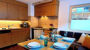 A modern kitchen with wooden cabinets, a dining table set for four, and a window with a view of the countryside. - Ferienwohung Chasa Max, (Samnaun-Plan) by Interhome (Samnaun)