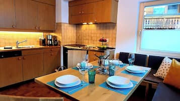 Una cocina moderna con armarios de madera, una mesa de comedor para cuatro personas y una ventana con vistas al campo.