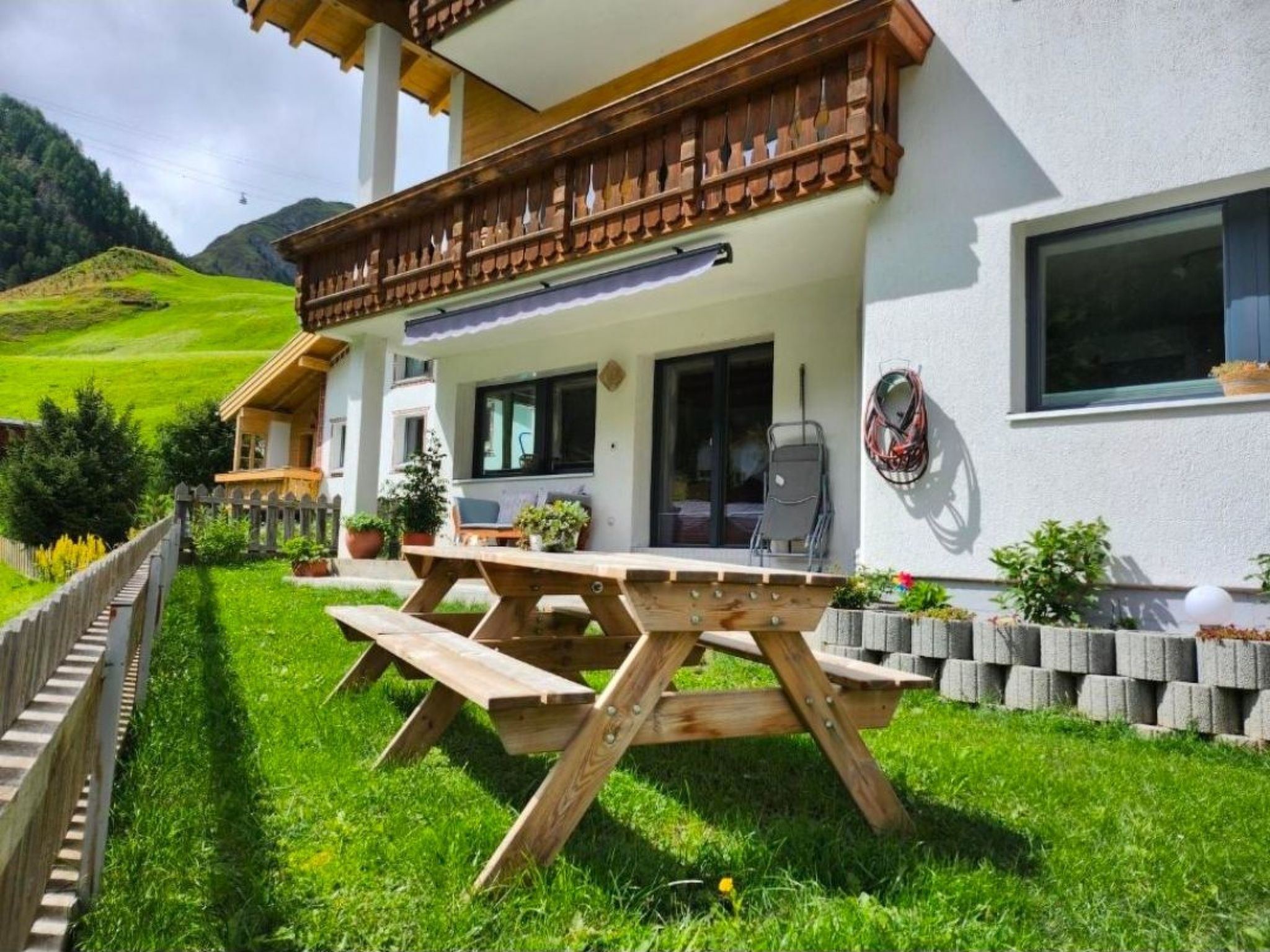 A chalet-style building with a wooden deck, picnic table, and a mountain view.