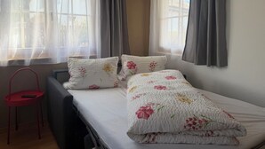 A bedroom with a bed, two pillows, a chair, and a window with curtains. - Chasa Bazzi, (Scuol) by Interhome (Scuol)