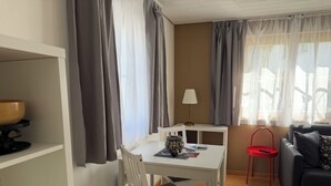 A room with a dining table, a chair, a small table with a lamp, a sofa, and a red chair. - Chasa Bazzi, (Scuol) by Interhome (Scuol)