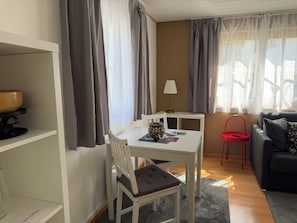 A room with a dining table, a chair, a small table with a lamp, a sofa, and a red chair. - Chasa Bazzi, (Scuol) by Interhome (Scuol)