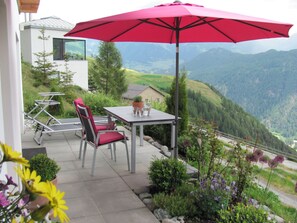 A patio with a table and chairs, an umbrella, and a view of a mountainous landscape. - Caviezel, (Tschlin) by Interhome (Tschlin)