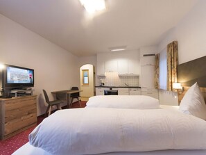 A hotel room with a bed, a desk, a television, a kitchenette, and a bathroom. - Appartements Alpin Live, (Samnaun-Laret) by Interhome (Samnaun)
