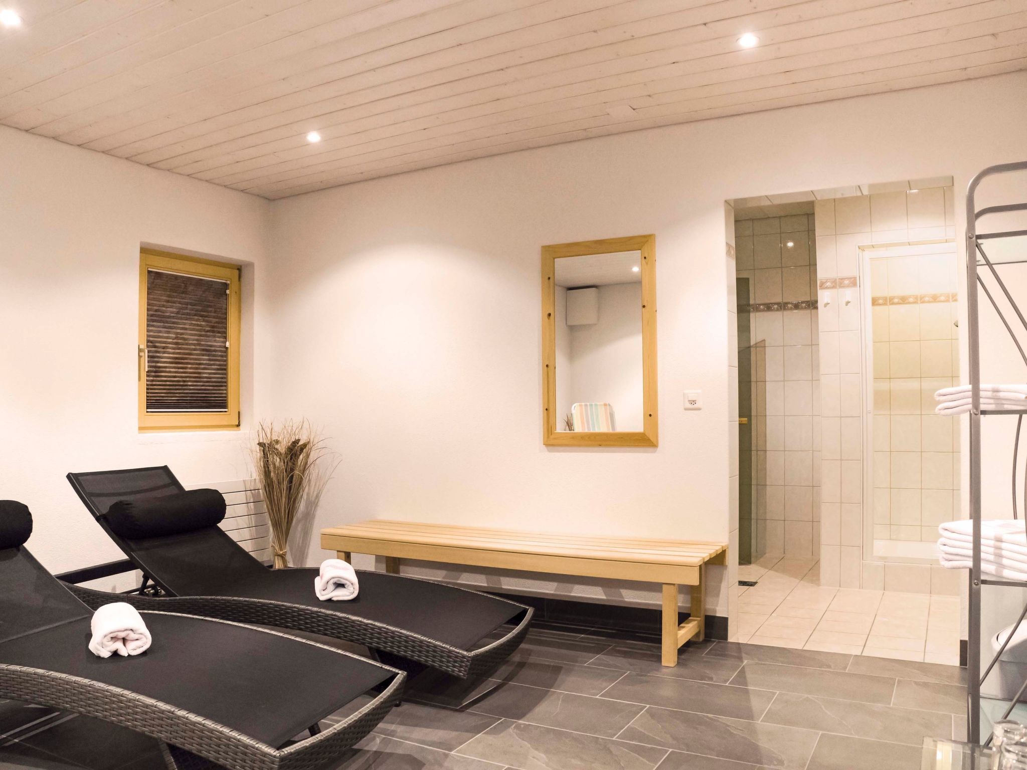 Une salle de spa équipée de deux fauteuils, d’un banc, d’un miroir et d’un espace douche.