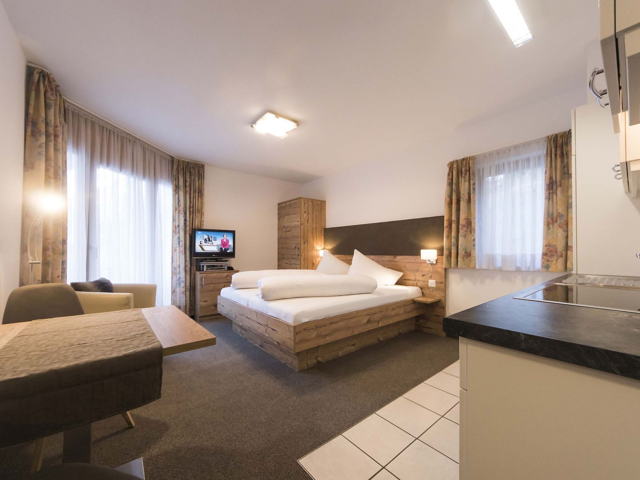 Een hotelkamer met een bed, bureau, televisie en kitchenette.