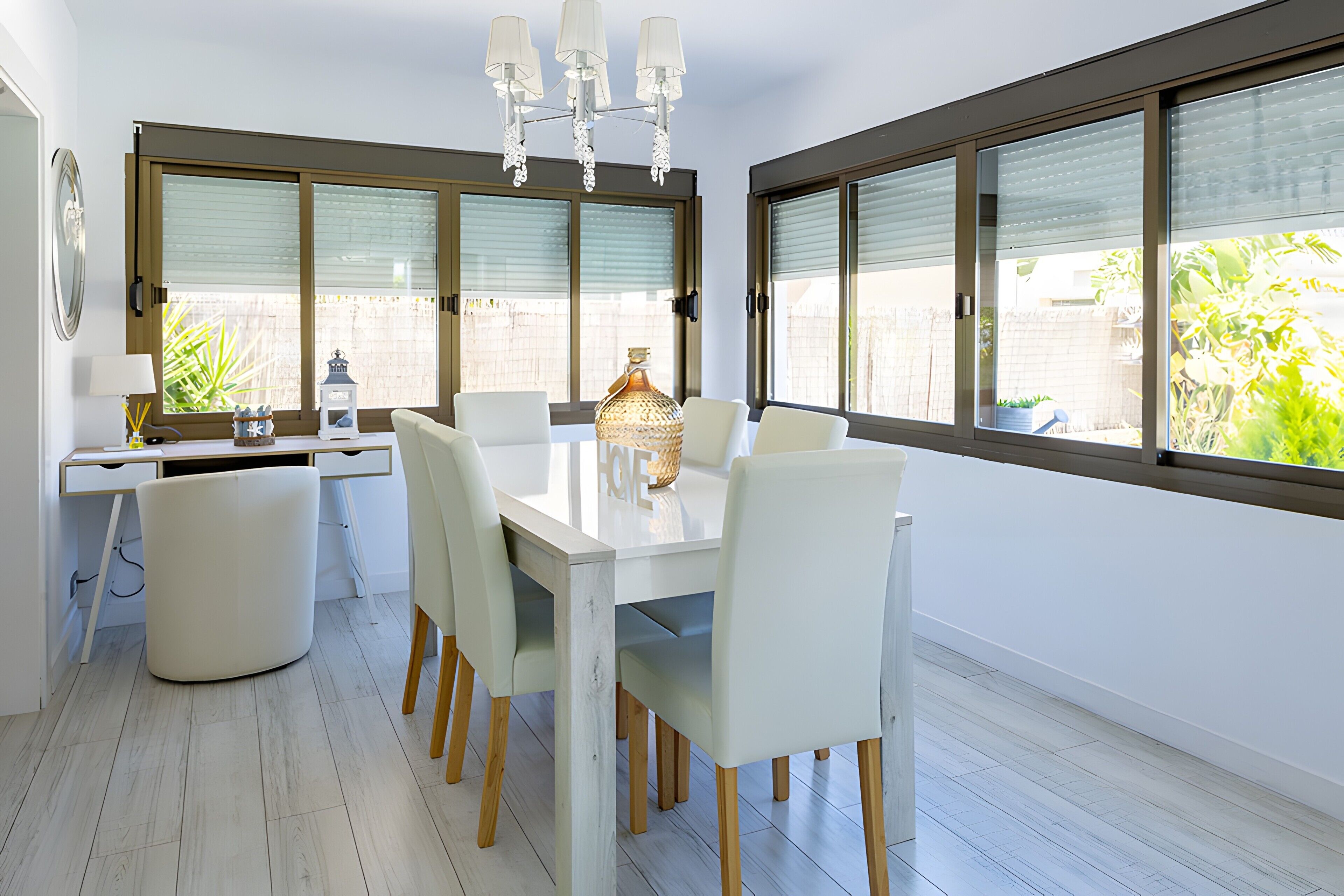 A modern dining area with a white table, chairs, and a chandelier.