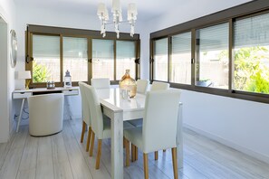 Ein moderner Essbereich mit einem weißen Tisch, Stühlen und einer Chandelier.