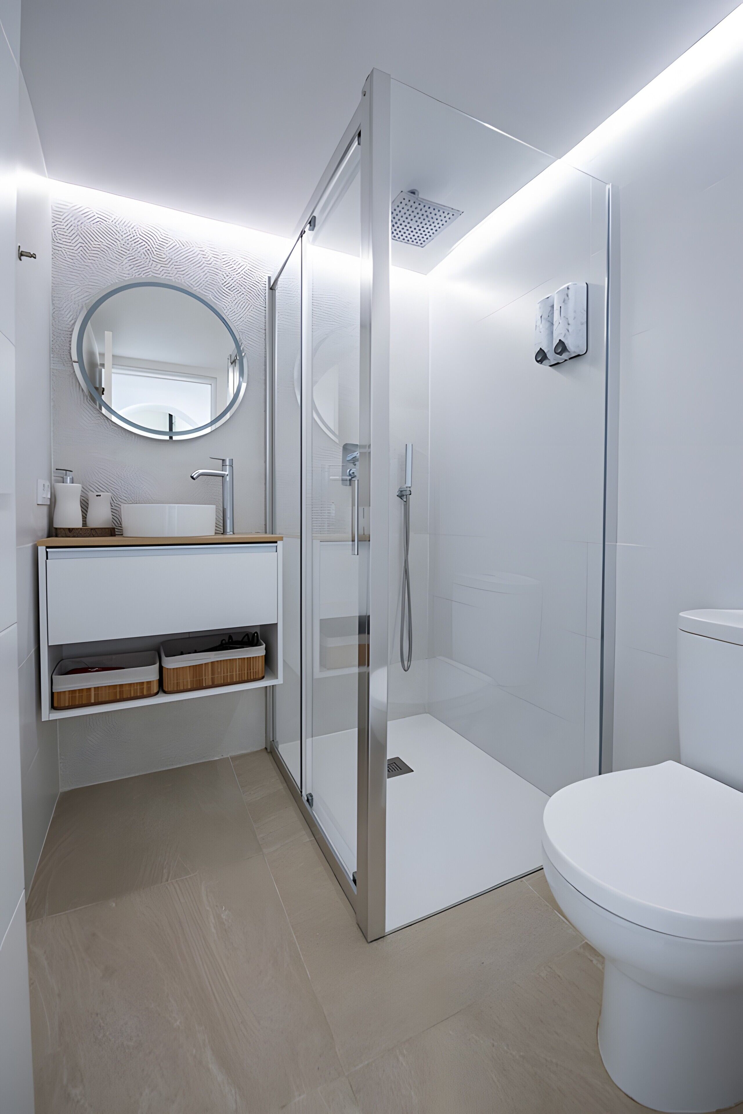 Et moderne badeværelse med en glasbrusekabine, et hvidt toilet og en vask med spejl og opbevaring.