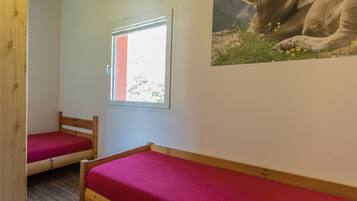 A room with two wooden beds, a window, and a wall-mounted picture.