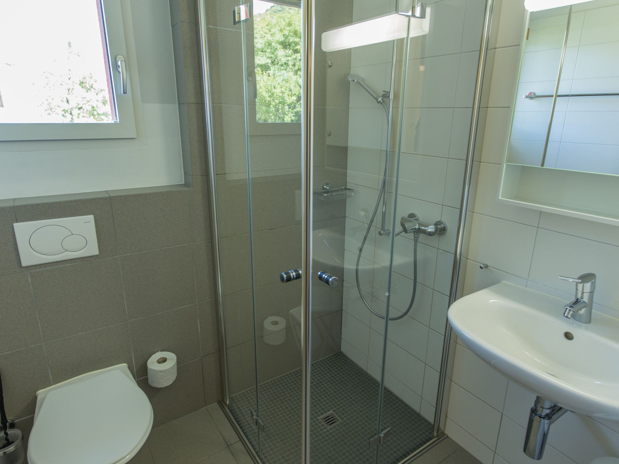 Un bagno con doccia vetro, un water e un lavandino.