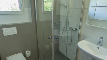 Un bagno con doccia vetro, un water e un lavandino.