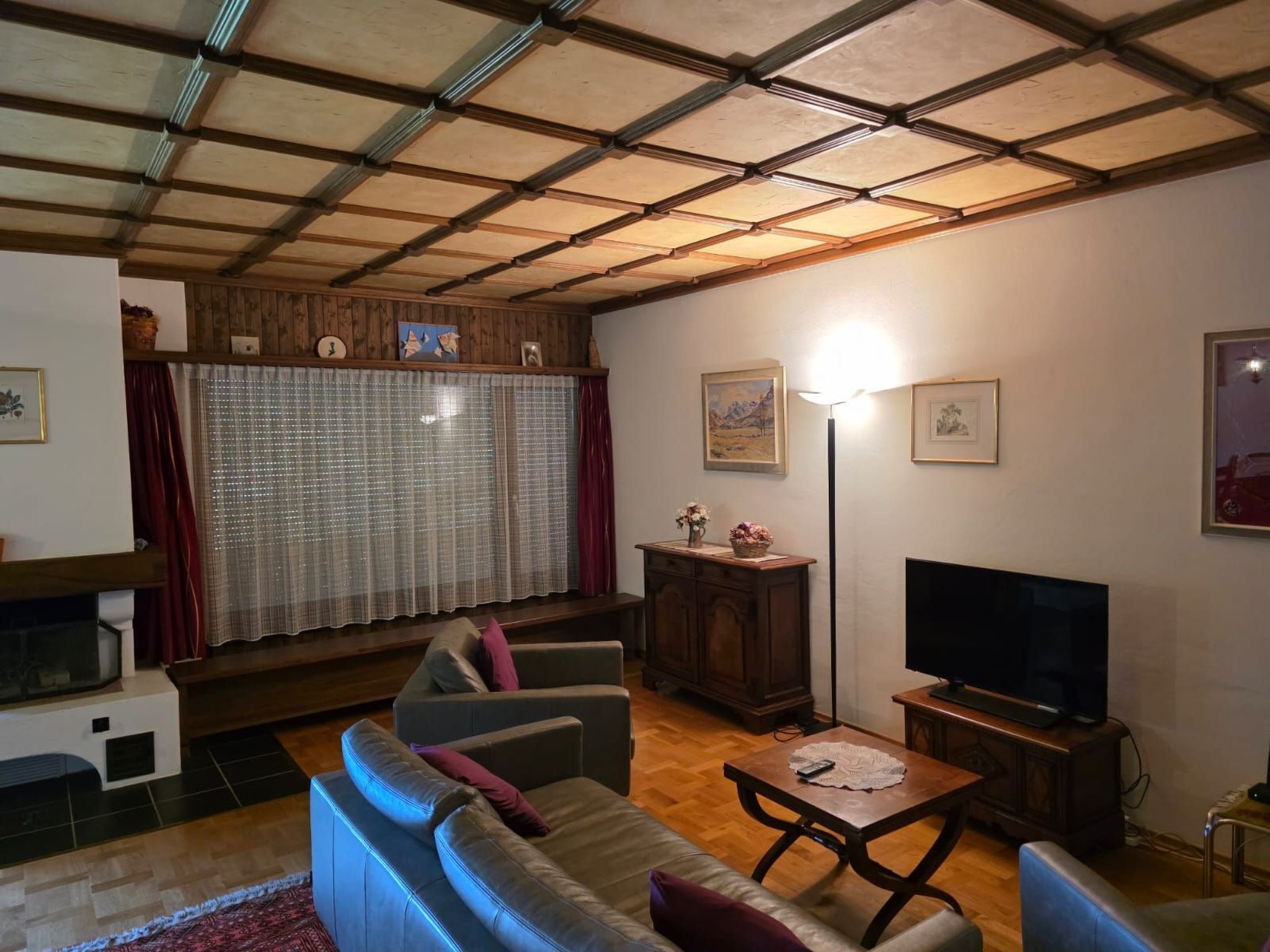 A living room with a sofa, television, wooden cabinet, and a fireplace.
