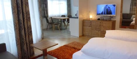 Une chambre d’hôtel avec un lit, un bureau, une télévision et, au fond, un coin repas.