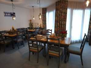 A dining area with wooden tables and chairs, a coffee station, and a view of the outdoors through large windows. - Appartements Alpin Live, (Samnaun-Laret) by Interhome (Samnaun)