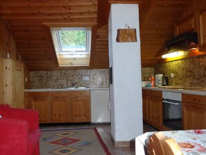 A compact kitchen with wooden cabinets, a built-in oven, and a window above the sink. - Chasa Quadra, (Tarasp) by Interhome (Tarasp)