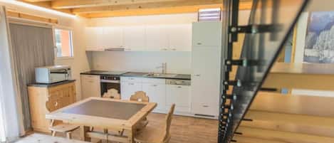 Une cuisine moderne avec des meubles blancs, une table à manger avec des chaises et un plancher en bois.