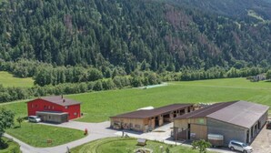 A rural property with a red building, a wooden barn, and a green field. - Agrotourismus Bauernhof Puntetta, (Müstair) by Interhome (Müstair)