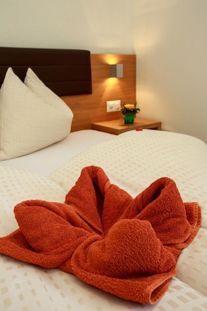 A hotel room with a neatly made bed, a wooden headboard, a nightstand with a lamp, and a small potted plant. - Apart Lischana, (Samnaun-Laret) by Interhome (Samnaun)