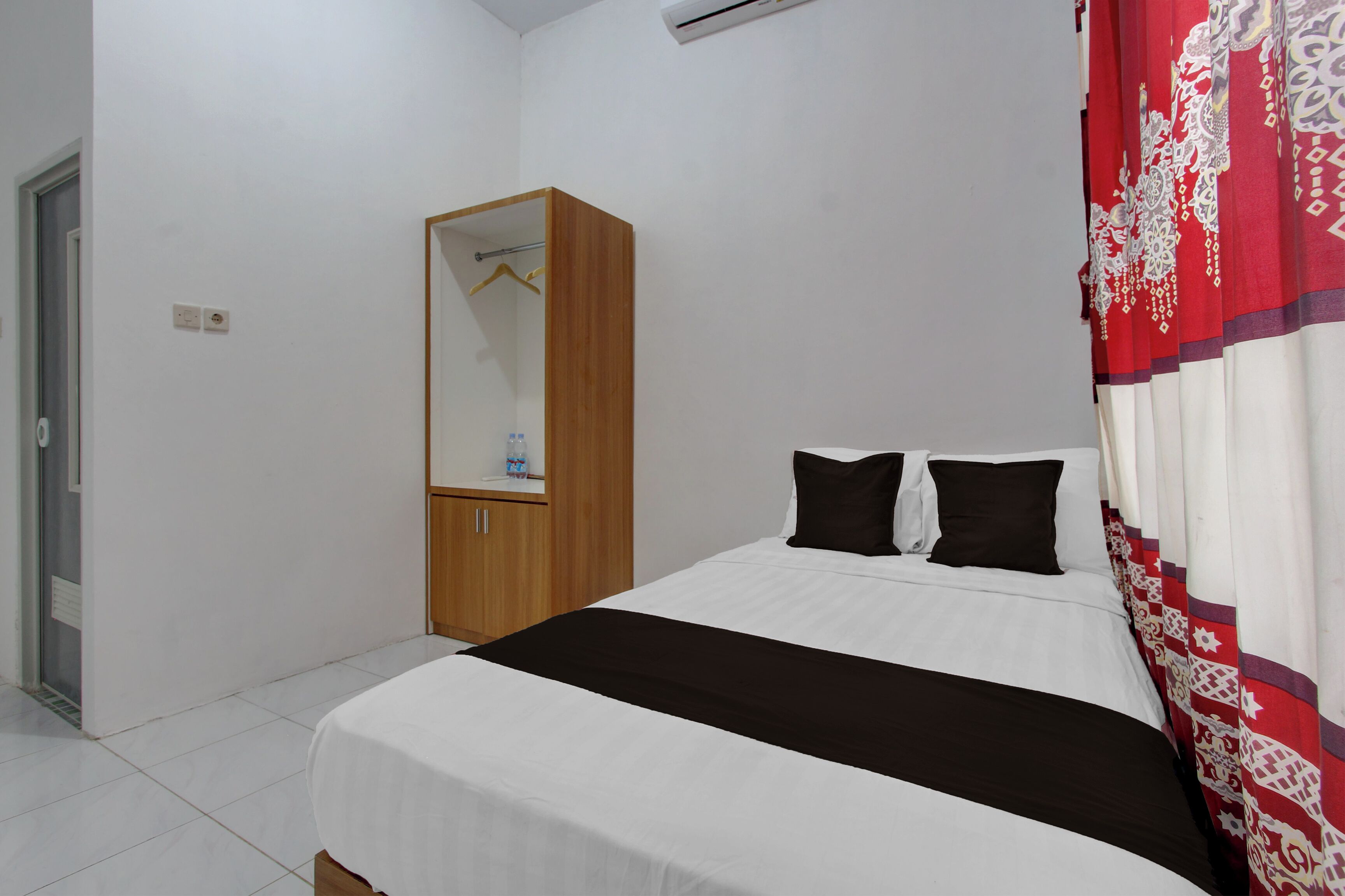 A bedroom with a bed, a wardrobe, a mirror, and a curtain.