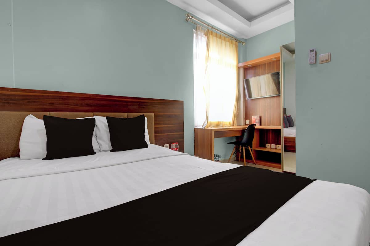 A hotel room with a large bed, a desk, and a wardrobe.
