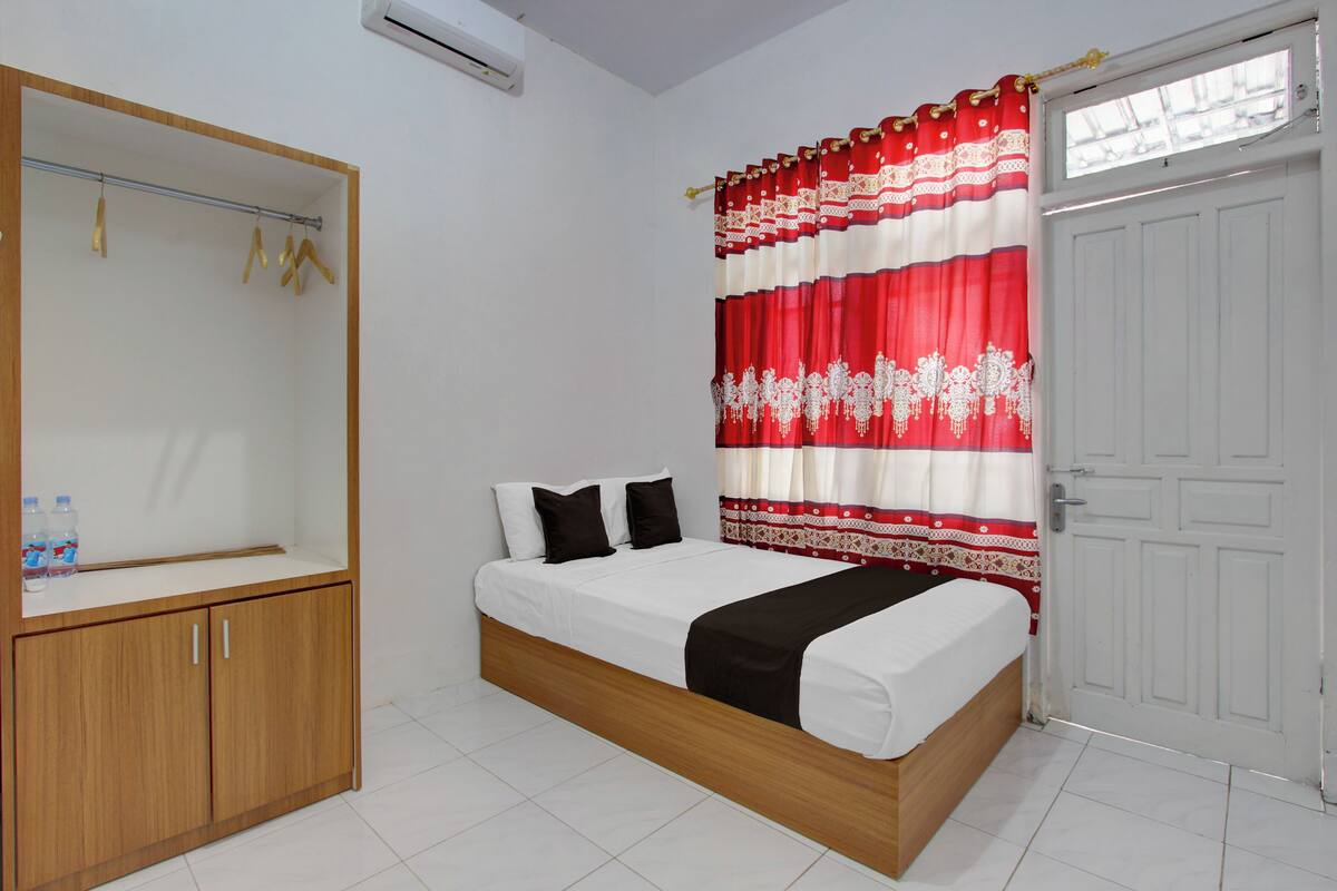 A bedroom with a bed, a wardrobe, a mirror, and a door.
