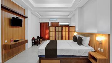 Quarto de hotel moderno com uma cama grande, cabeceira de madeira, mesas de cabeceira, televisão de tela plana e um guarda-roupa embutido.