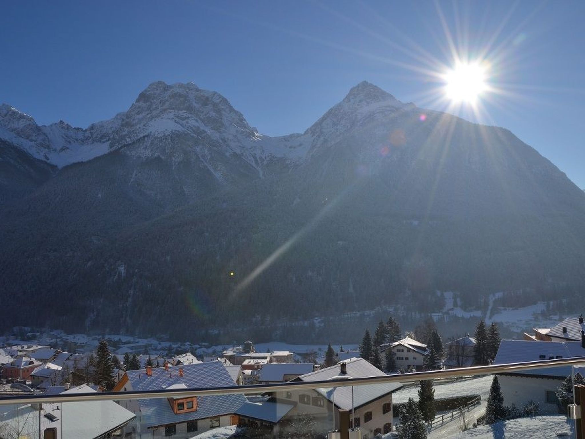 Un paysage de montagne avec des sommets enneigés et un soleil éclatant.