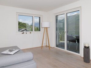 Ein modernes Zimmer mit einer Couch, einer Stehlampe und großen Fenstern mit Blick auf die Berge.