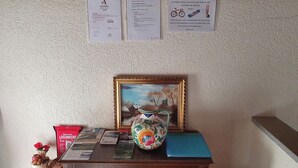 Ein Holztisch mit einem gerahmten Gemälde, einer Vase, Broschüren und einer roten Schachtel.