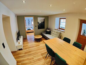 A modern interior with a wooden dining table, green upholstered chairs, a sofa, and a painting on the wall. - Chasa Salnuun, (Samnaun-Compatsch) by Interhome (Samnaun)