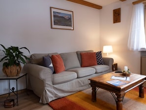 Sala de estar com sofá, mesa de centro, luminária e planta.