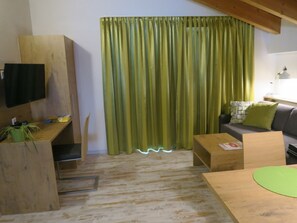 A living room with a wooden desk, a television, a sofa, and a green curtain. - Chasa Madlaina, (Samnaun-Dorf) by Interhome (Samnaun)