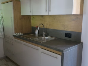 A kitchen with a stainless steel sink, wooden countertop, and white cabinets. - Chasa Madlaina, (Samnaun-Dorf) by Interhome (Samnaun)