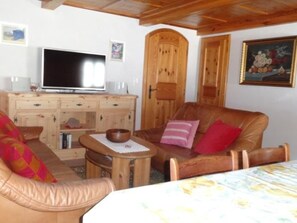 A cozy room with a sofa, a chair, a television, wooden cabinets, and a painting on the wall. - Chasa Quadra, (Tarasp) by Interhome (Tarasp)