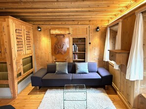 A cozy cabin interior with a sofa, bookshelf, and wooden walls. - Chasa Stupan 1. Obergeschoss, (Ardez) by Interhome (Ardez)