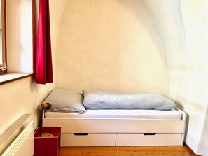 A small, white, single-bed room with a wooden floor, a red curtain, and a window. - Chasa Stupan 1. Obergeschoss, (Ardez) by Interhome (Ardez)