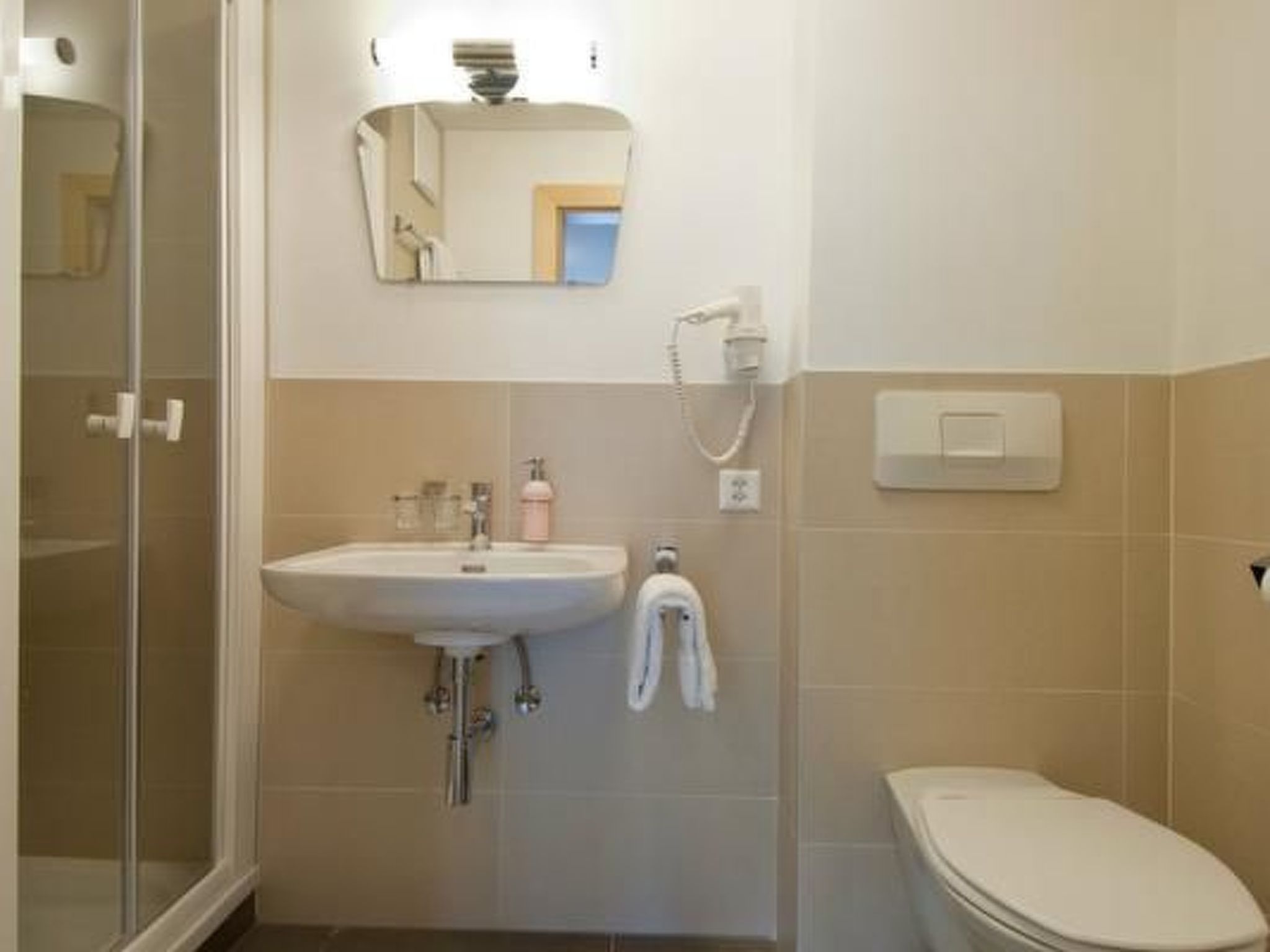 Een badkamer met een wastafel, spiegel, handdoekhouder en toilet.