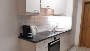 Cozinha compacta com cafeteira, chaleira e eletrodomésticos modernos.