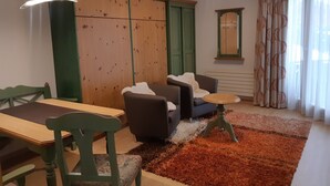Sala de estar com um armário de madeira, dois sofás, uma mesa redonda e um tapete estampado.