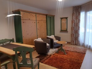 A living room with a wooden cabinet, two sofas, a round table, and a patterned rug. - Appartements Alpin Live, (Samnaun-Laret) by Interhome (Samnaun)