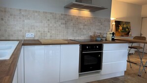 Una cocina moderna con horno empotrado, un lavamanos y una encimera con tabla de cortar.