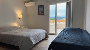 Un dormitorio con una cama, una mesita de noche, aire acondicionado, un cartel y una puerta corrediza de vidrio que da a un balcón.