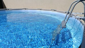 Una piscina cristalina con escalera, rodeada por un muro con textura.