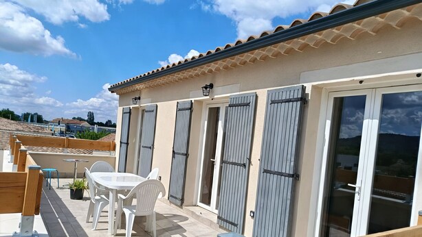 Una terraza con una mesa y sillas, una planta en maceta y vistas del entorno.