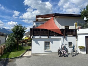 Ein zweistöckiges Gebäude mit einer roten Markise, einem draußen abgestellten Fahrrad und Bergen im Hintergrund.