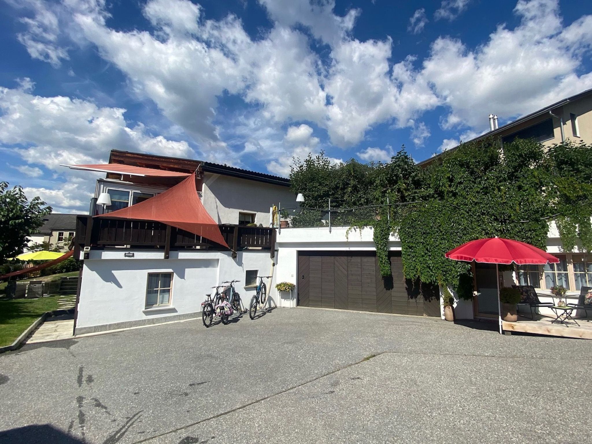 A modern building with a garage, bicycles parked outside, and a red umbrella.