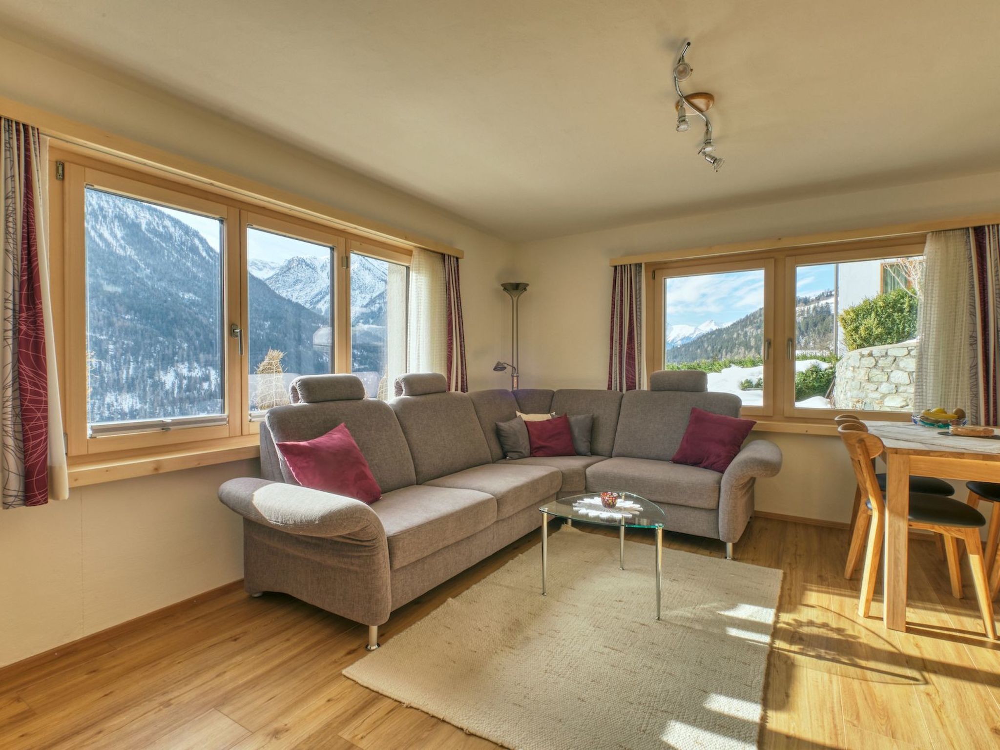 A modern living room with a sectional sofa, a glass coffee table, and large windows offering mountain views.