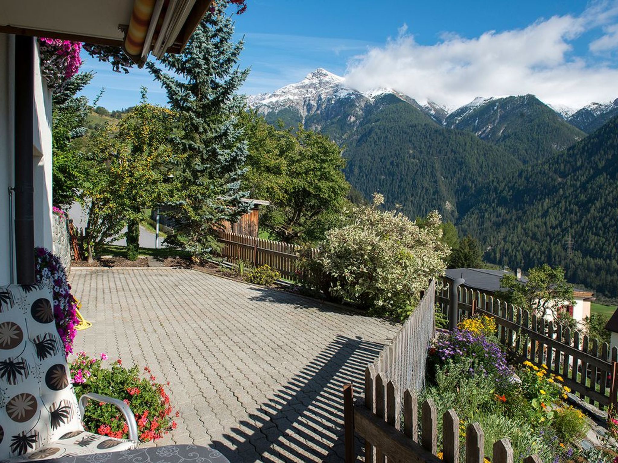 A mountain view from a balcony with a wooden fence and potted plants.